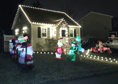 residential property at night with christmas lights and christmas decorations in the front yard,