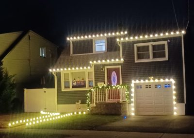 christmas lights on a residential property blue home with red door, white lights,